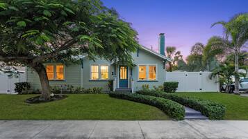 A two-story house with a front yard, a tree, and a white fence.