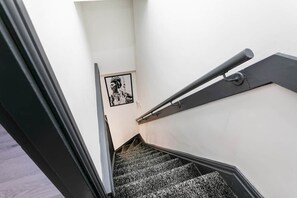 Eine Treppe mit Handlauf, ein kleines gerahmtes Bild an der Wand und ein Türrahmen oben.