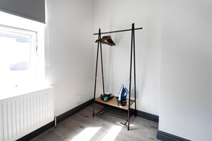 Ein Zimmer mit einem Heizkörper, einem schwarzen Metallgestell mit Ablagefläche und einem Fenster für natürliches Licht.