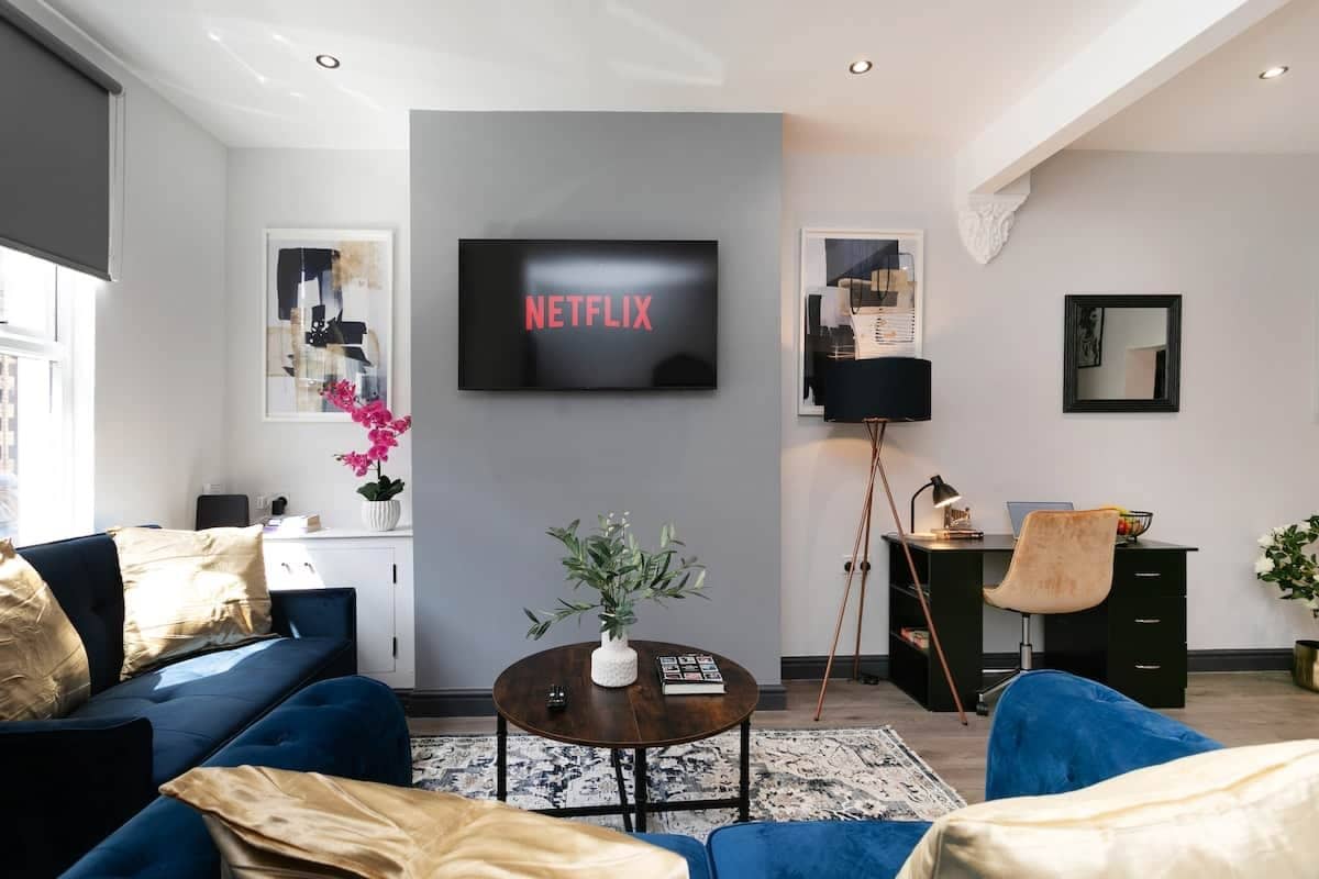 A modern living room with a sofa, coffee table, and a flat-screen TV mounted on the wall.