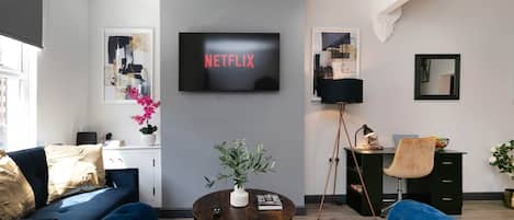 A modern living room with a sofa, coffee table, and a flat-screen TV mounted on the wall.