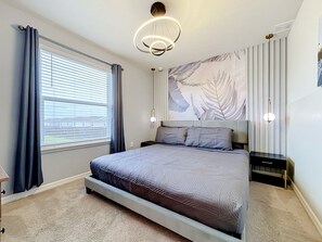 A bedroom with a bed, a window with curtains, a wall-mounted light fixture, and a radiator. - Windsor Island | 10BR Luxury Haven + Game Room (Davenport)