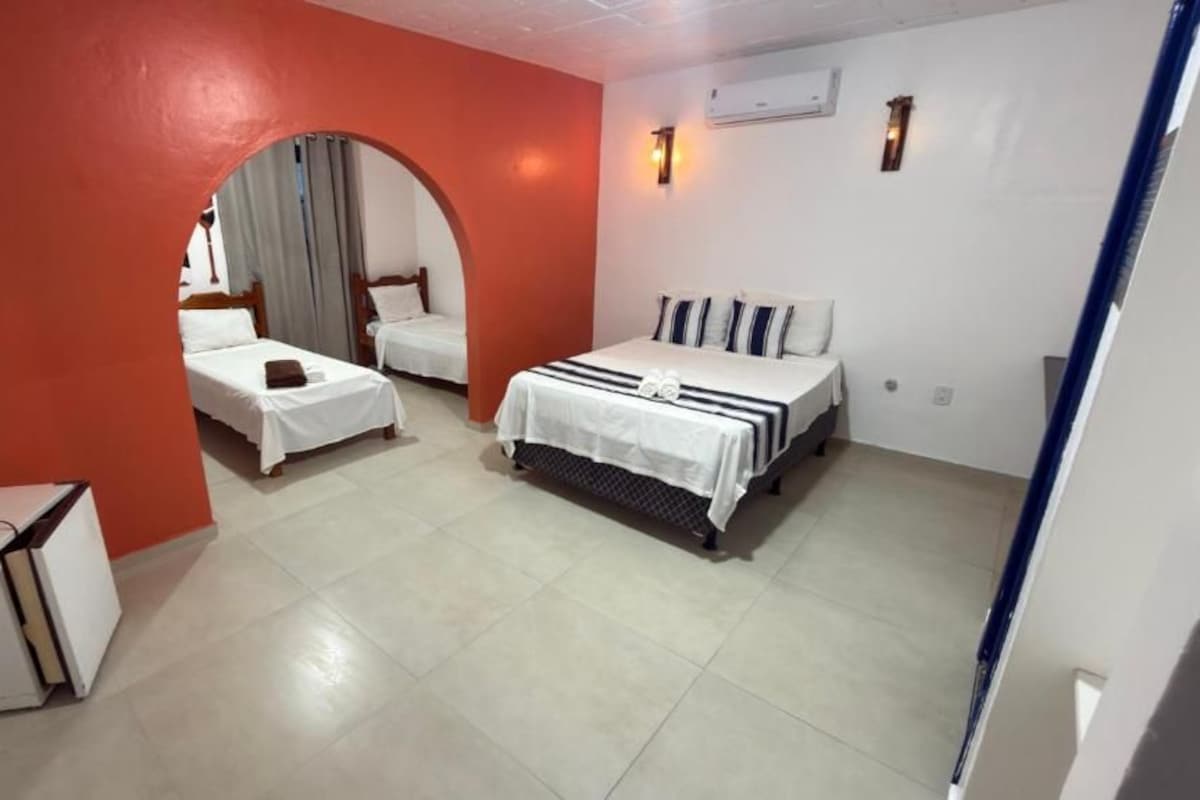 A hotel room with two beds, a small desk, and a tiled floor.