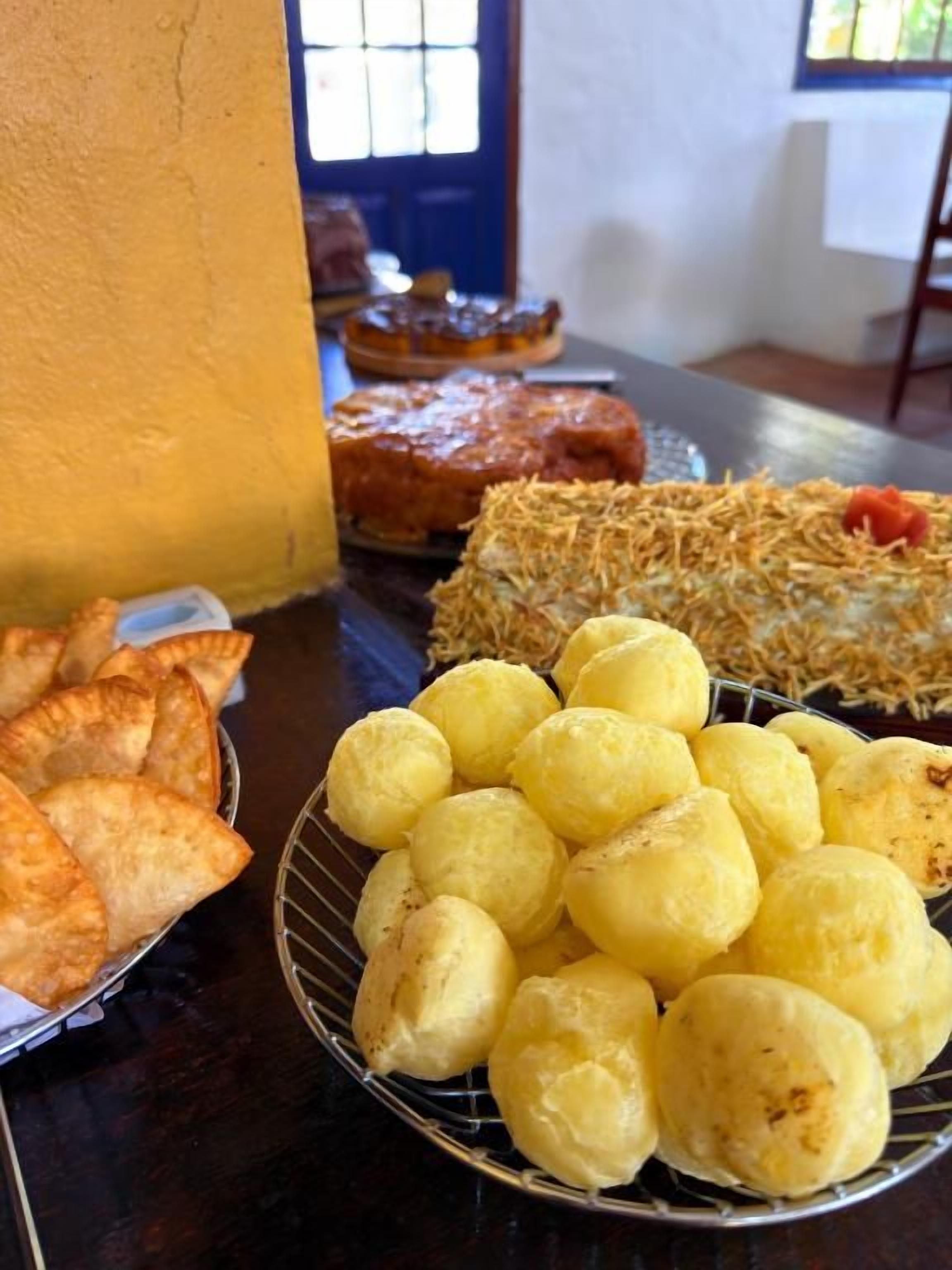 Ein Tisch mit verschiedenen Speisen, darunter Empanadas, Käsebällchen und ein Dessert.