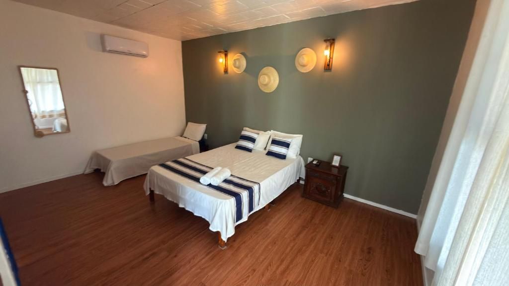A bedroom with a large bed, a smaller bed, a nightstand, and a mirror.