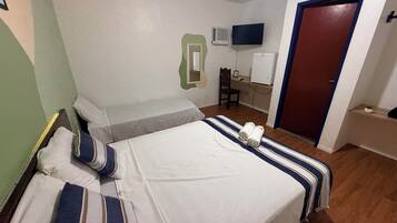 A hotel room with a bed, a desk, a chair, a television, and a door.