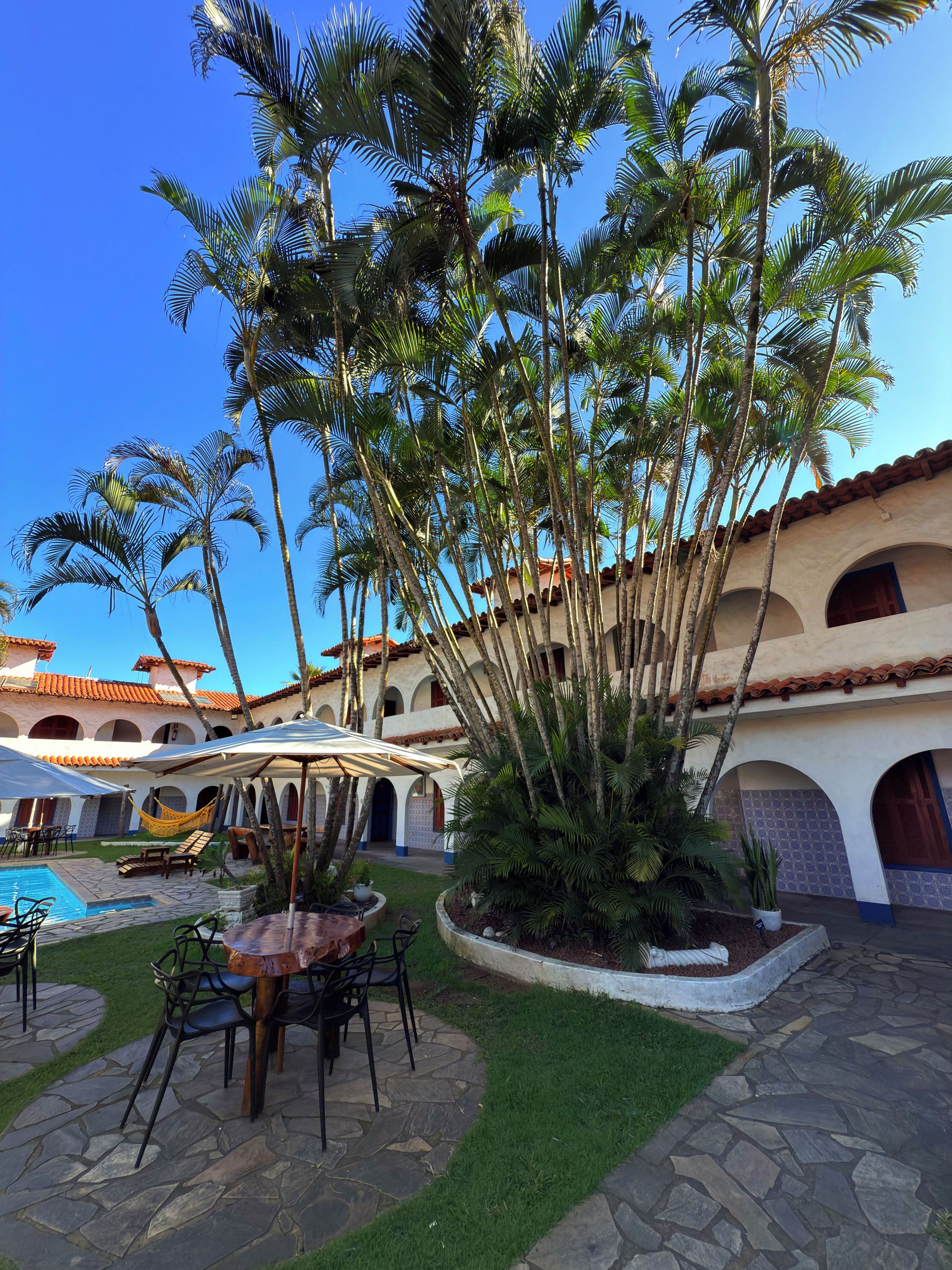 A courtyard with a pool, outdoor seating, and palm trees.
