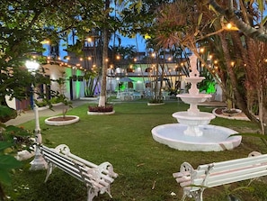 A well-maintained garden with a central fountain, benches, and string lights. - Pousada Puerta del Sol (Rio das Ostras)