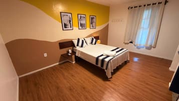 A bedroom with a bed, bedside tables, and a window with curtains.