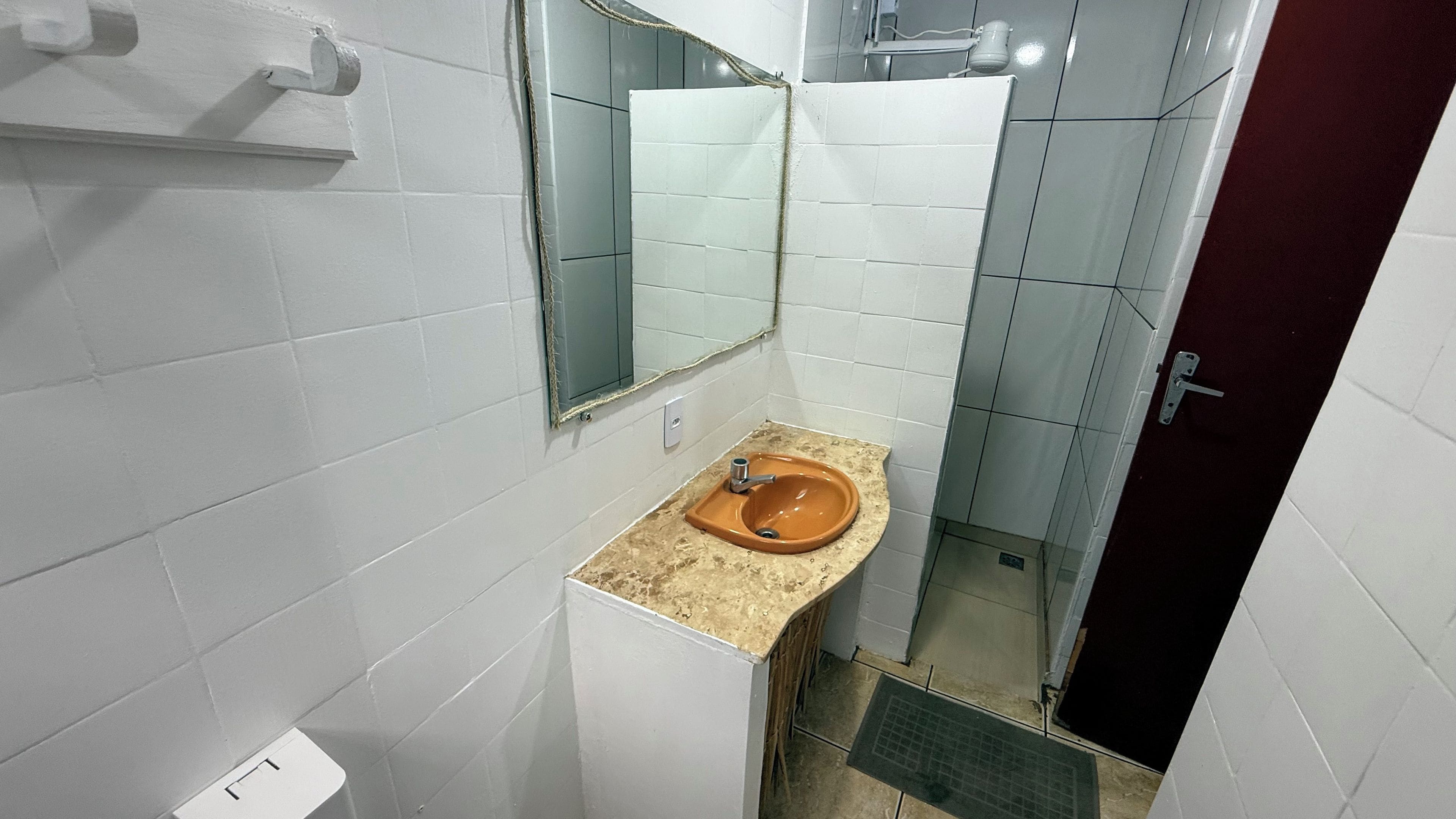 A bathroom with white tiled walls, a brown sink, and a mirror.