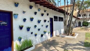 A building with a white exterior, blue doors, and a series of blue planters on the wall.