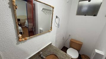 A bathroom with a toilet, sink, mirror, and towel rack.