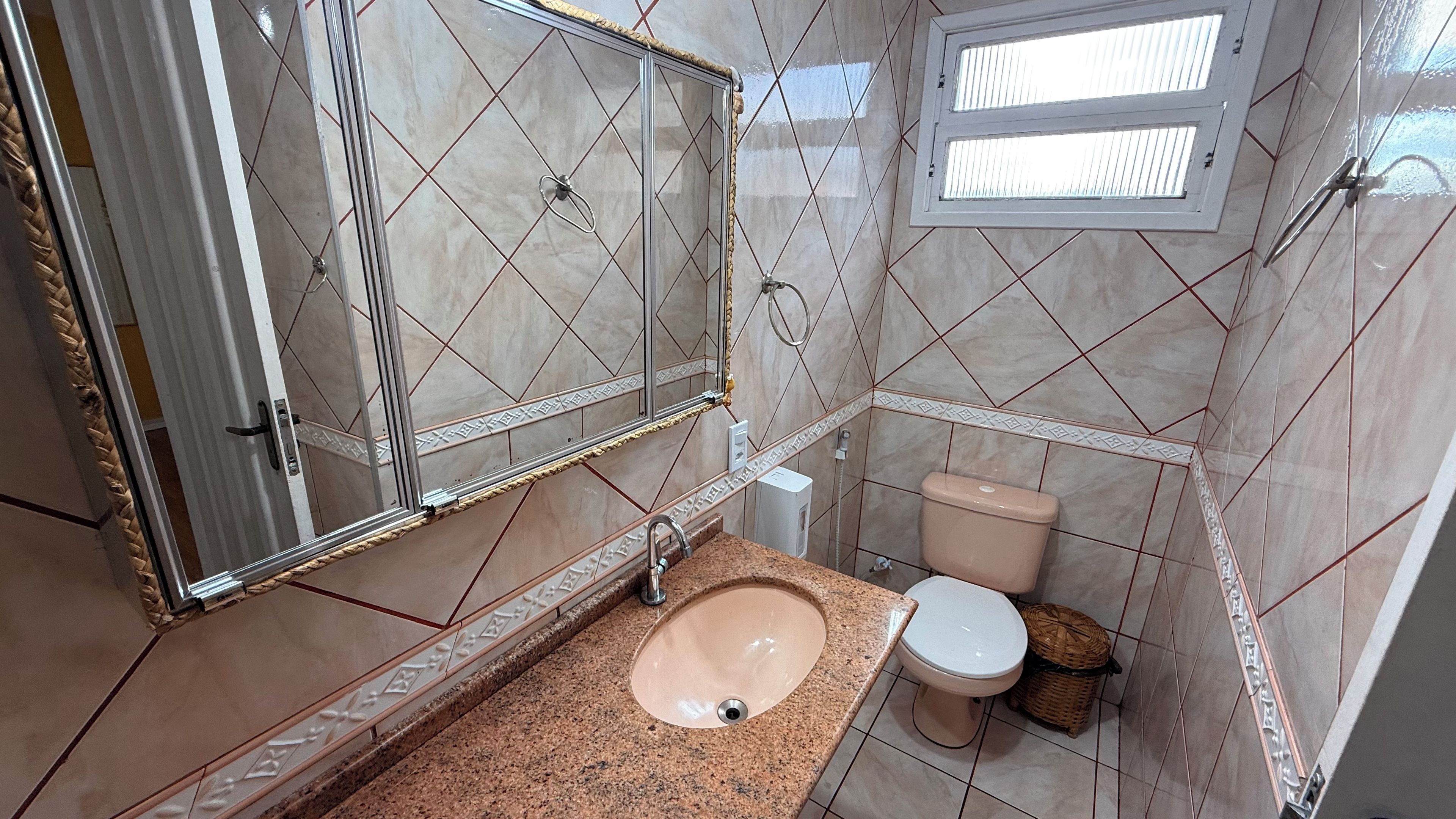 A bathroom with a sink, toilet, and a window above the toilet.