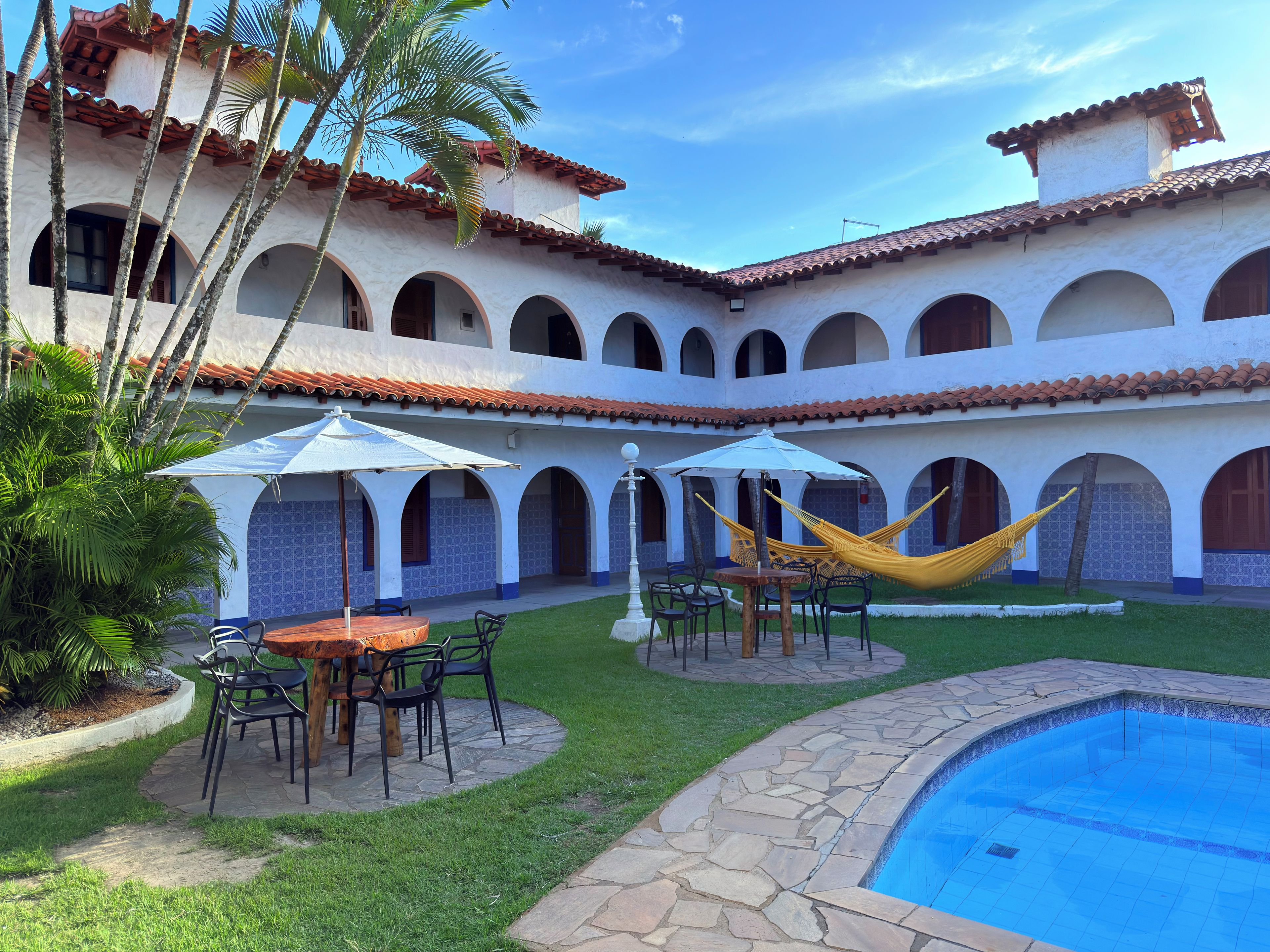 Un patio con piscina, mobiliario exterior y hamacas.