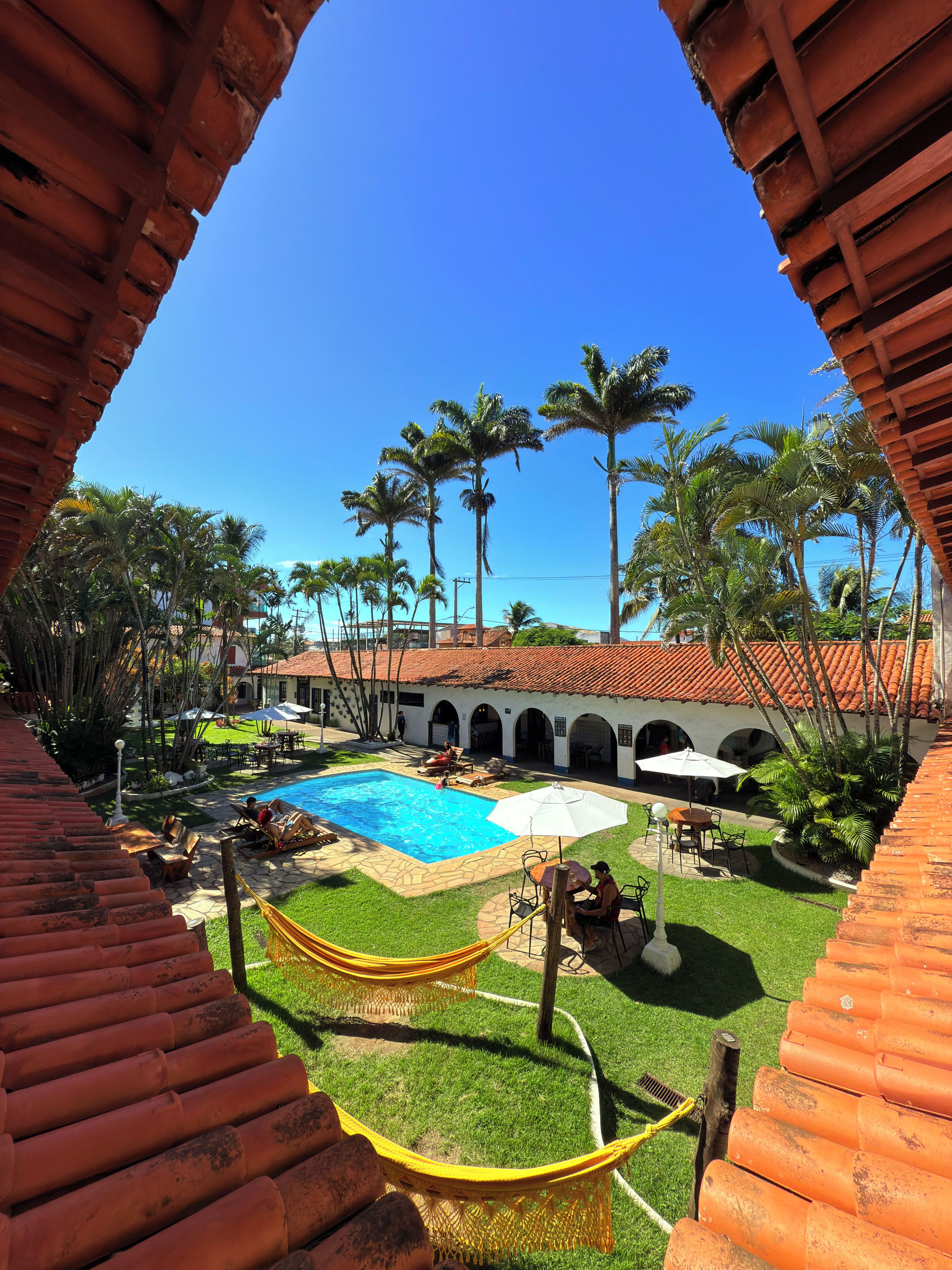 A courtyard with a swimming pool, outdoor seating, and palm trees.