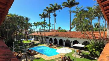 A courtyard with a swimming pool, outdoor seating, and palm trees.