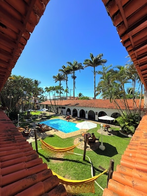 A courtyard with a swimming pool, outdoor seating, and palm trees.