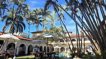 A courtyard with palm trees, a pool, and outdoor seating.