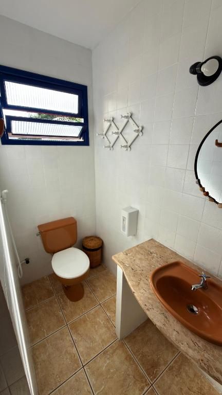 A small bathroom with a toilet, a sink, and a window.