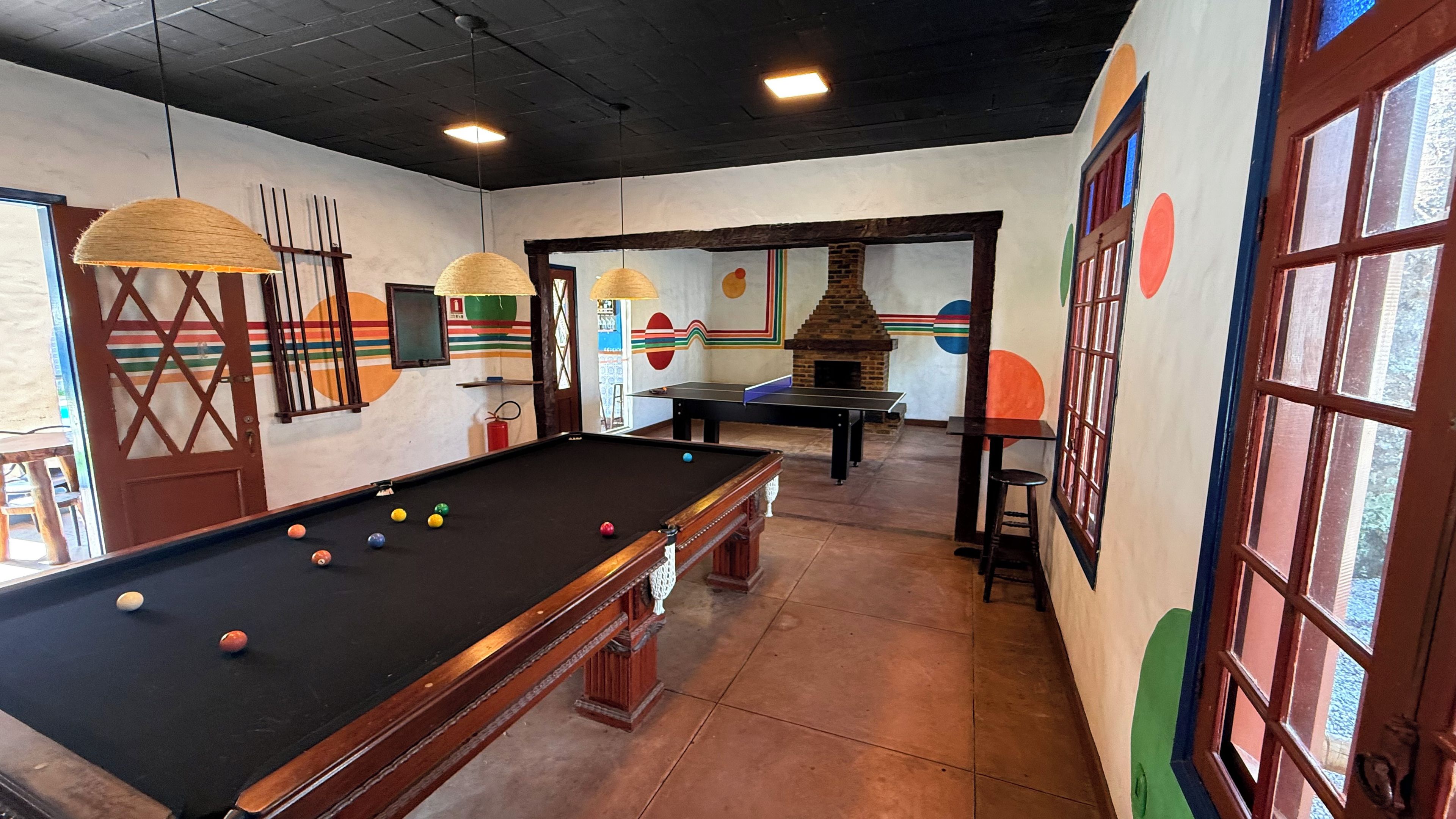 A billiards table with balls, a fireplace, and a door with a window.