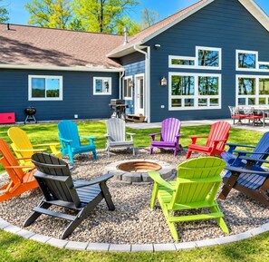 A blue house with a fire pit and colorful Adirondack chairs arranged around it. - Chain Of Lakes direct trail access / Free Firewood (Eagle River)