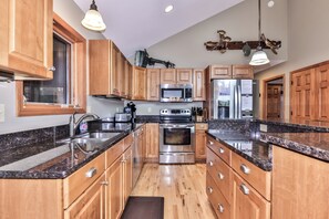 A modern kitchen with wooden cabinets, stainless steel appliances, and granite countertops. - Eagle River Chain – Steps to Golf & Lake Life! (Eagle River)