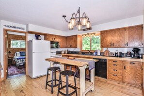 Eine Küche mit Holzausstattung, einem Kühlschrank, einer Spüle und einem Essbereich mit Hockern.