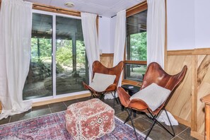 A room with two leather armchairs, a patterned ottoman, and large windows with curtains. - Secluded 3 Story Lake Front Home with large deck, private pier, C/A & More! (Eagle River)