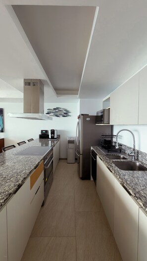 A modern kitchen with a granite countertop, stainless steel appliances, and a built-in oven. - Península Sky Residence | Ixtapa Beachfront (Ixtapa Zihuatanejo)
