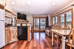 A kitchen with wooden cabinets, a black dishwasher, and a flat-screen TV mounted above the counter. - Private Full Rec Lake Launch & Dock! Free Firewood (Eagle River)