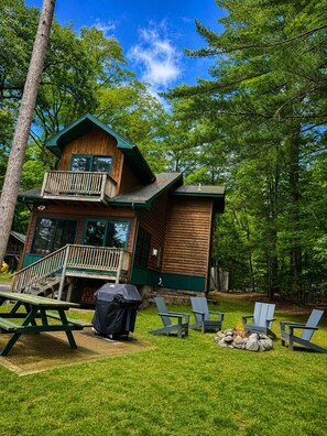 Eine Hütte mit Balkon, Feuerstelle und Sitzgelegenheit im Freien.