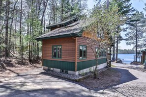 Une cabane avec un toit en pente, un revêtement en bois et un petit espace porche.