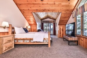 Ein Schlafzimmer mit Holzboden, einem Bett, einem Nachttisch, einer Bank und einem Fernseher.