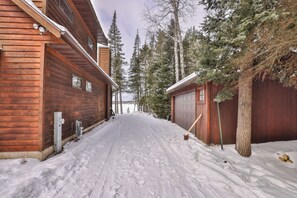 Eine Holzhütte mit Garage und einer verschneiten Auffahrt.