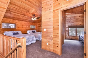 Un chalet confortable avec deux chambres, un plafond en bois et un petit balcon.