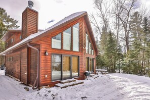 A wooden cabin with large windows, a chimney, and a snow-covered ground. - Sandy Bottom | Secluded | UTV/Snowmobile Access (conover)