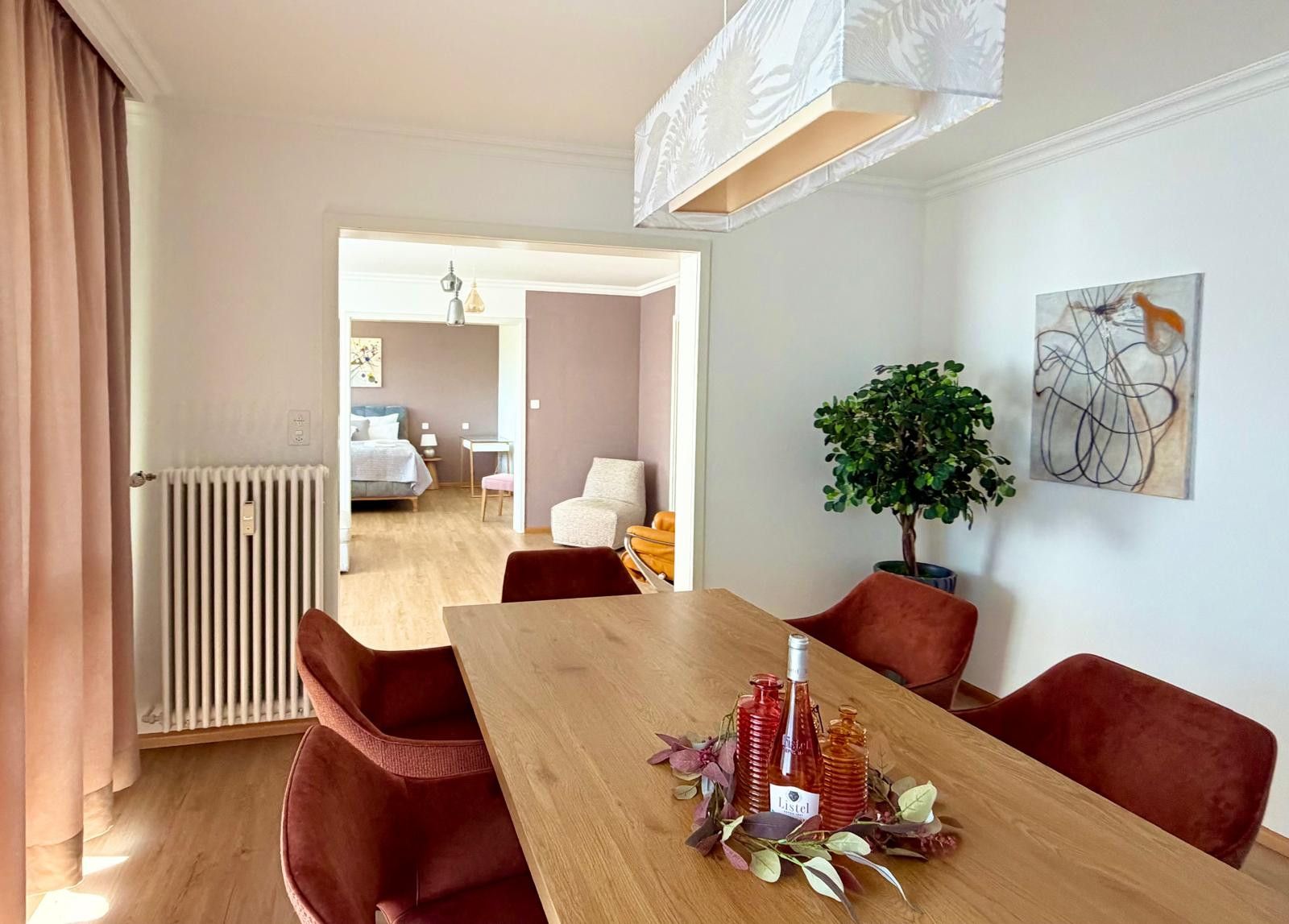 Un coin repas avec une table en bois, des chaises rouges et une bouteille de vin Listel.