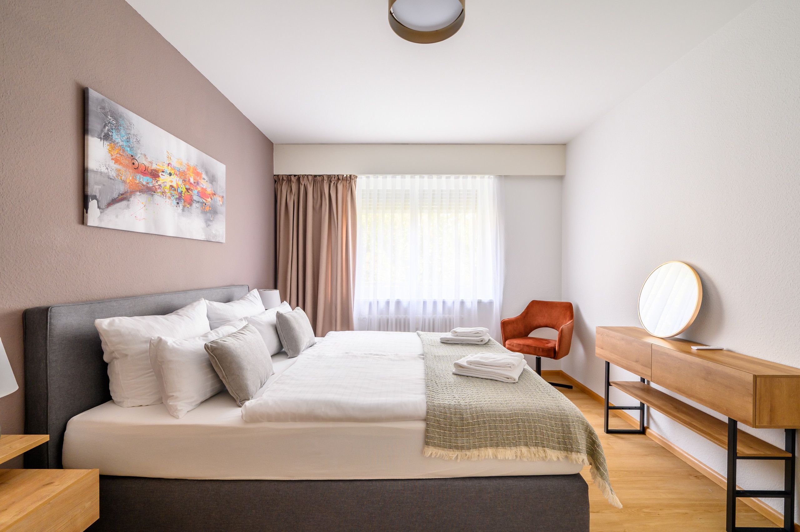 Une chambre d’hôtel moderne avec un grand lit, un bureau, une chaise et un tableau au mur.