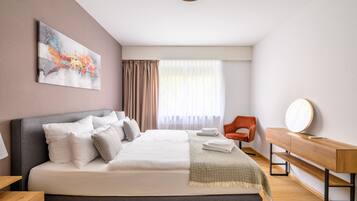 Une chambre d’hôtel moderne avec un grand lit, un bureau, une chaise et un tableau au mur.