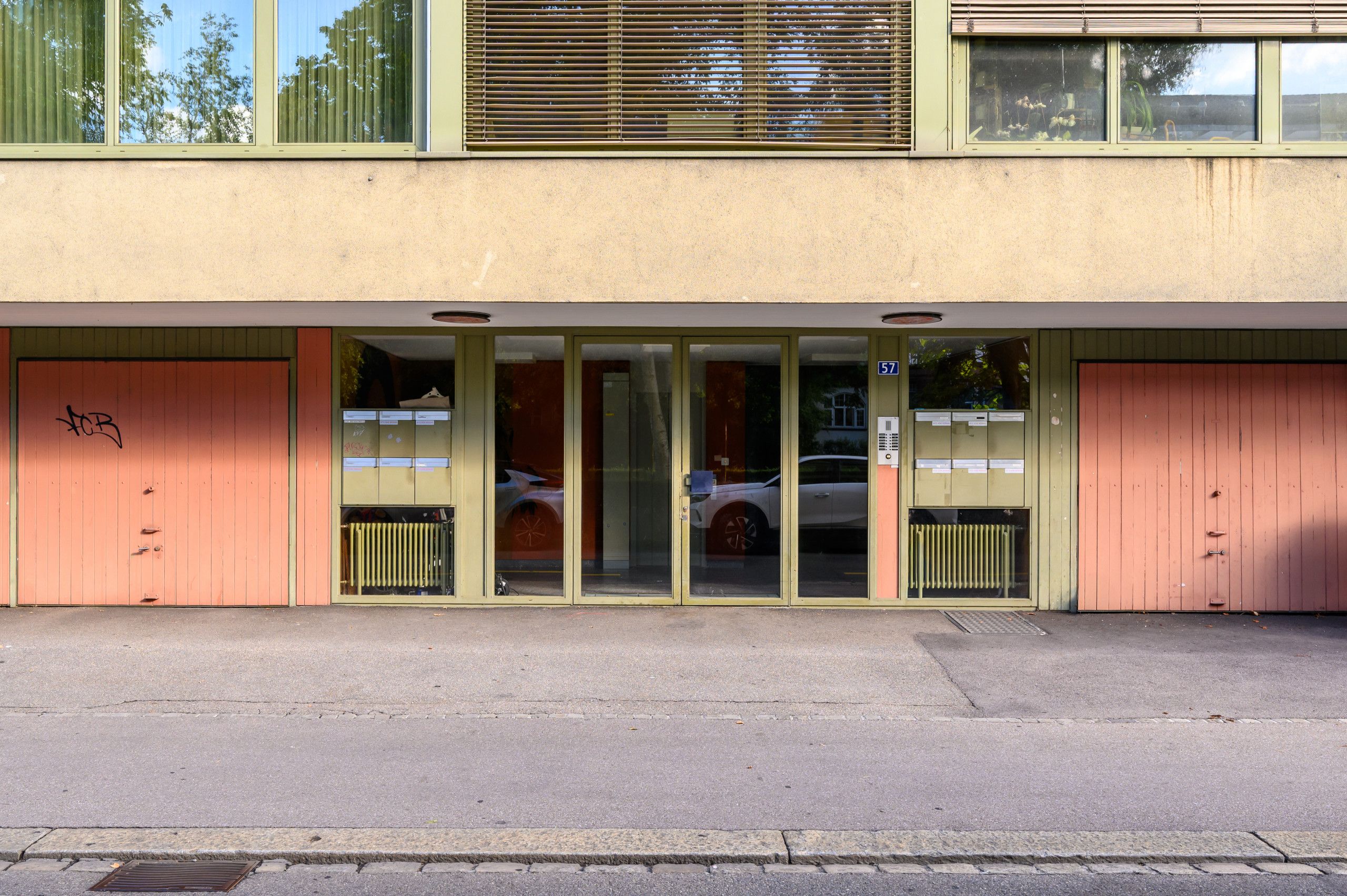 A building with a set of glass doors, a number '57' sign, and a metal grate on the ground.