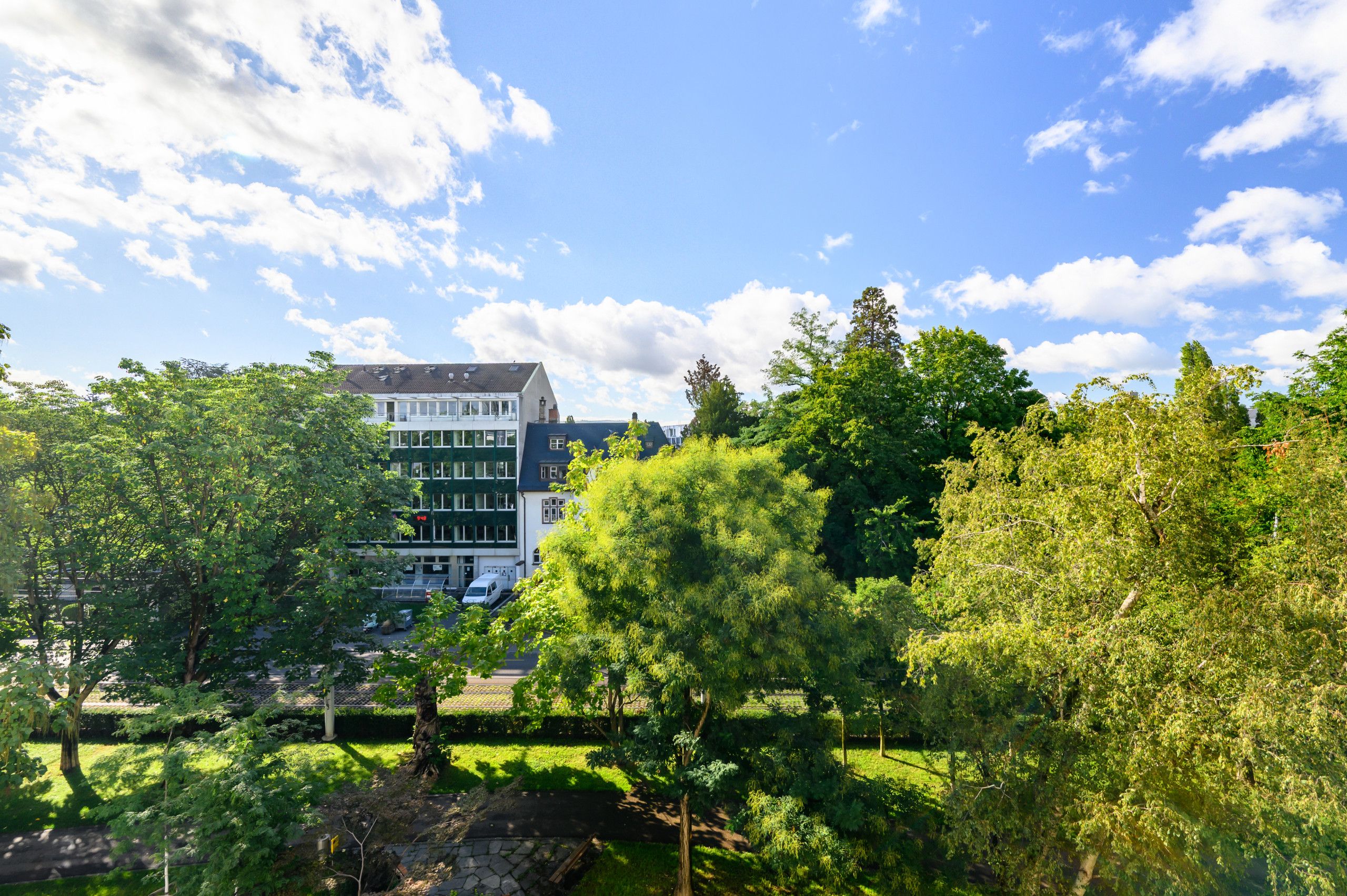 Un immeuble à plusieurs étages, doté d’une architecture moderne, entouré d’une végétation luxuriante et d’arbres.