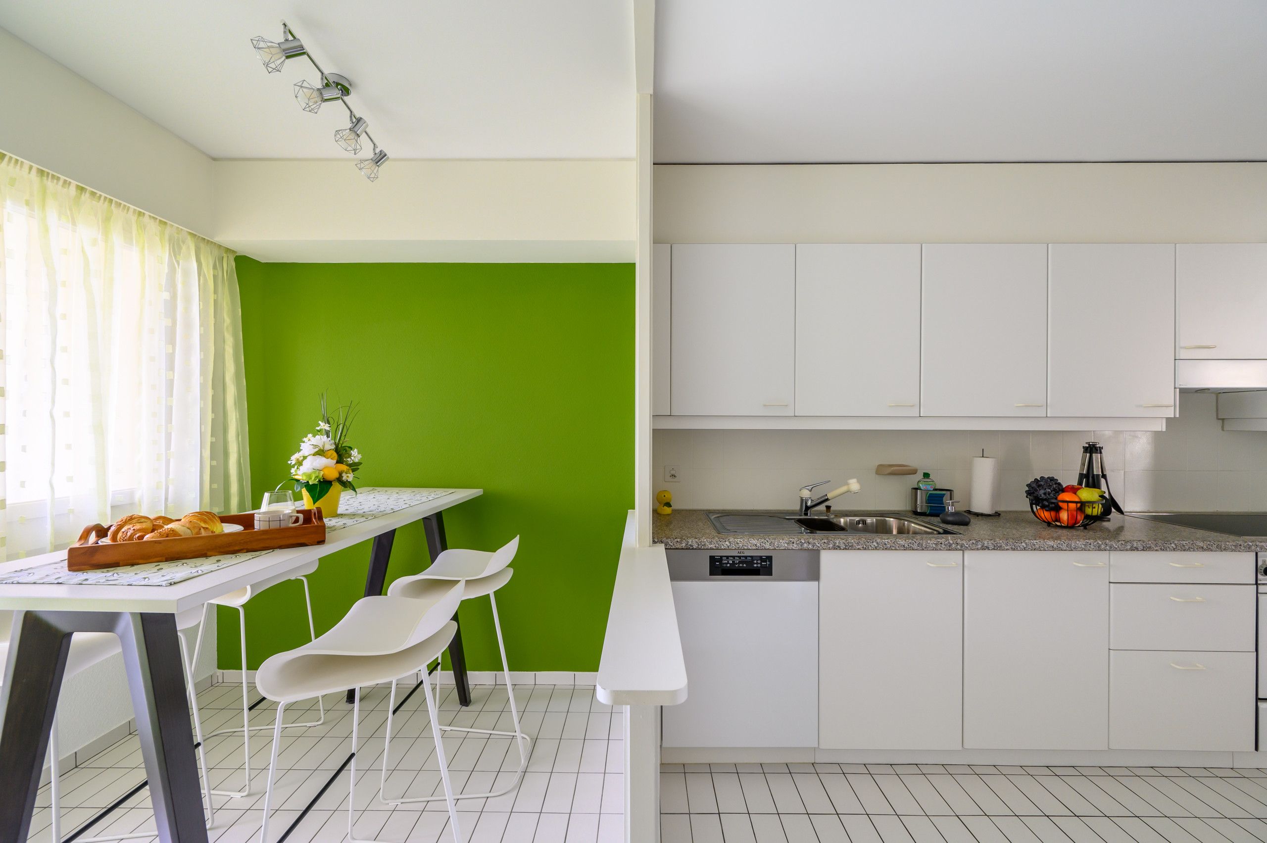 Una cucina moderna con mobili bianchi, un piano di lavoro in granito e una lavastoviglie incassata.