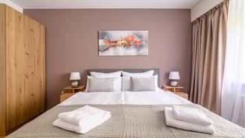 Une chambre d’hôtel avec un grand lit, deux tables de chevet avec des lampes, une armoire en bois et un tableau au mur.