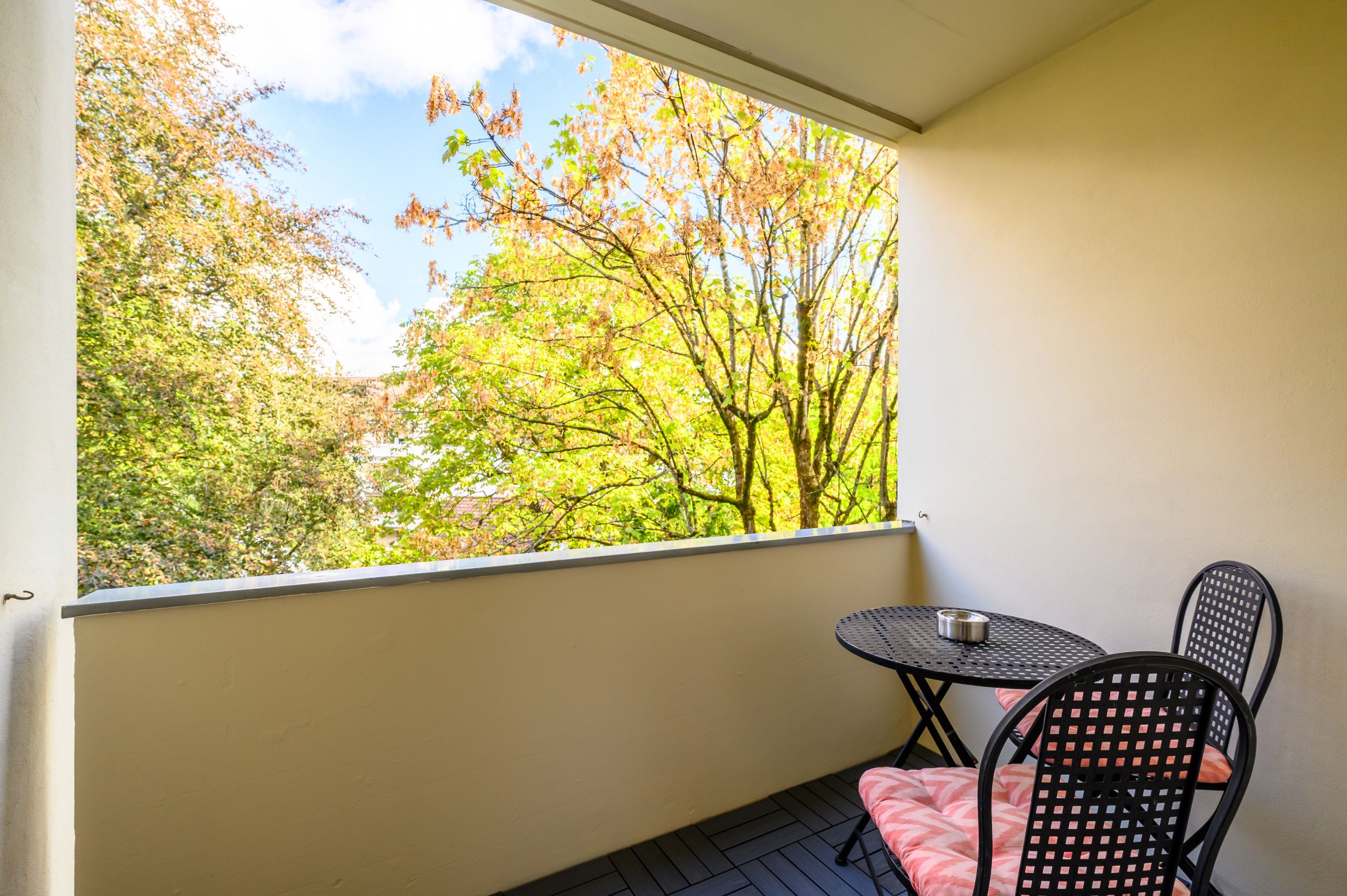 Un balcon avec une table et des chaises, offrant une vue sur un paysage arboré.