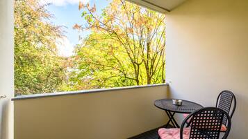 Un balcon avec une table et des chaises, offrant une vue sur un paysage arboré.
