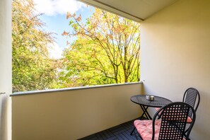 Ein Balkon mit Tisch und Stühlen mit Blick auf eine von Bäumen gesäumte Landschaft.