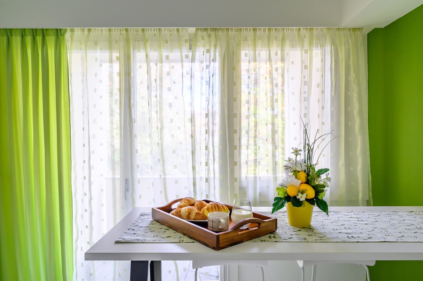 Une table avec un plateau de pâtisseries, un vase de fleurs et un verre d’eau.
