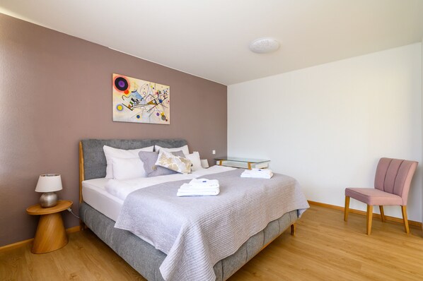 Ein Hotelzimmer mit Bett, Sessel, Nachttisch und einem Bild an der Wand.