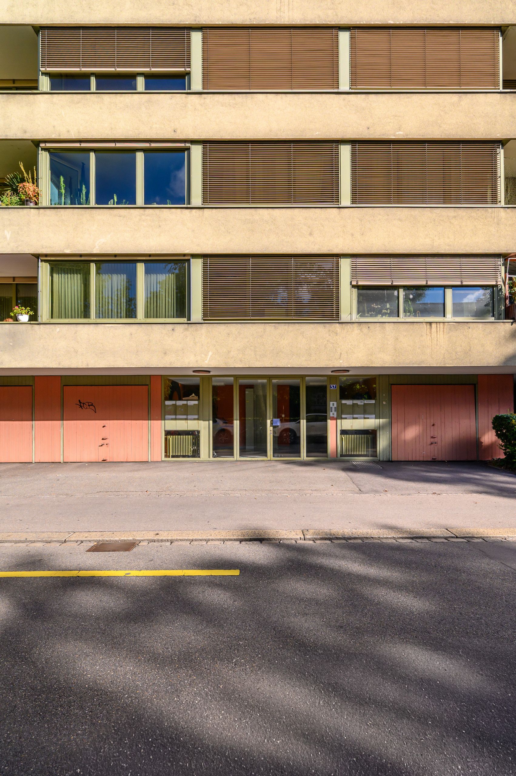Ein mehrstöckiges Gebäude mit einer flachen Fassade, großen Fenstern und einer Garage im Erdgeschoss.