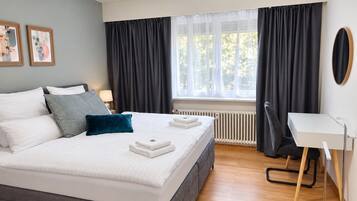 Une chambre d’hôtel moderne, dotée d’un grand lit, d’un bureau et offrant une vue sur l’extérieur.